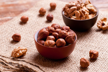 walnuts and hazelnuts in bowls on wooden background