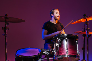 Handsome man drummer sitting and playing on his kit