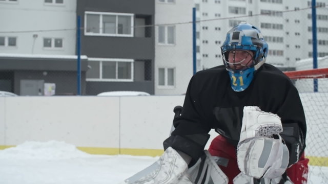 Ice hockey goaltender stopping a puck from going into his goal net during a play at outdoor rink 