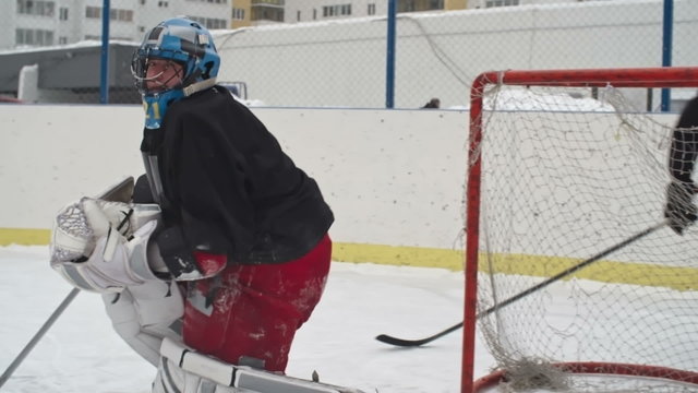 Hockey goaltender preventing the opposing team from scoring by catching a puck in slow motion 