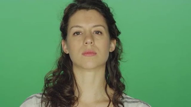 Young woman looking serious, on a green screen studio background