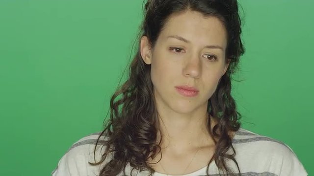 Young woman looking sad, on a green screen studio background