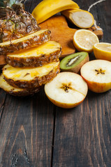 Fresh sliced pineapple and fruits on a wood table