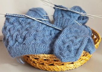 Hand knitting. Hat and mittens with surround pattern in a wicker basket
