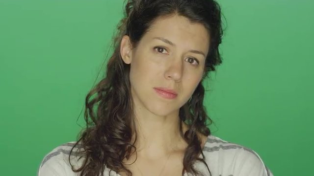 Young woman beginning to cry, on a green screen studio background