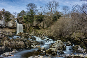 Wide angle view of Thornton Force Waterfall in the Yorkshire Dales National Park with small cascading waterfalls in foreground.