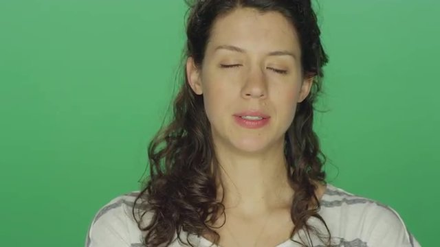 Young woman starting to feel better after crying, on a green screen studio background