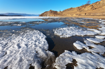 Baikal Lake. Sunny spring day. The ice floes are melting on a sandy beach