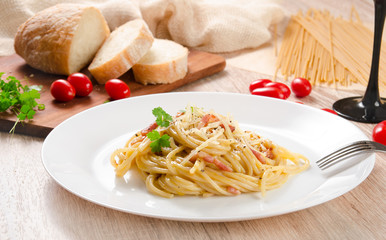 Pasta Carbonara with bacon on a white plate, wooden table, side view

