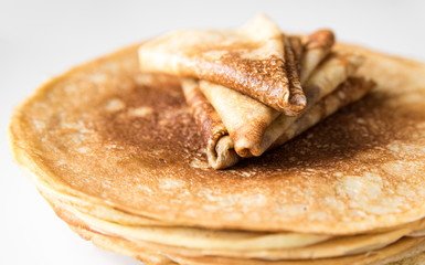 A stack of thin Russian pancakes and crepes folded triangle, close-up, isolated

