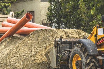 Bulldozer takes the sand where the sewer pipe.Reconstruction of sewerage system.