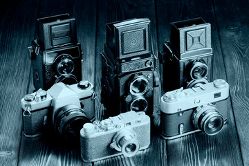 The old film cameras on the wooden table.