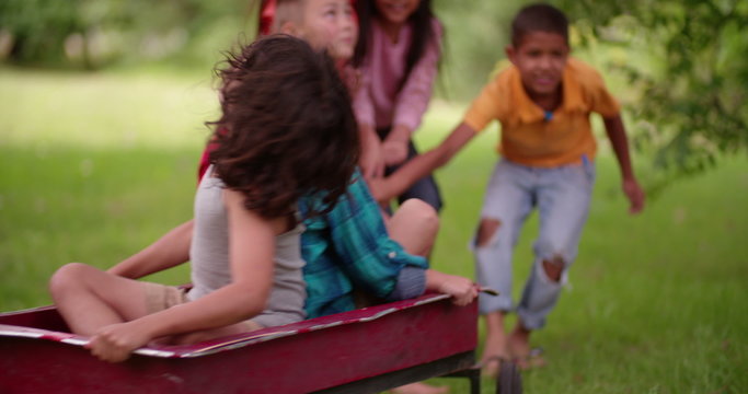 Childhood friends playing in a park together with a wagon