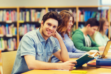 happy student boy reading book in library
