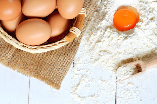 Eggs, flour and yolk on white desk