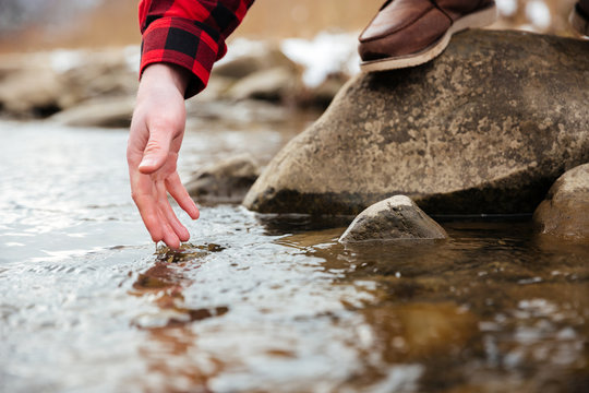 Male hand testing water in river