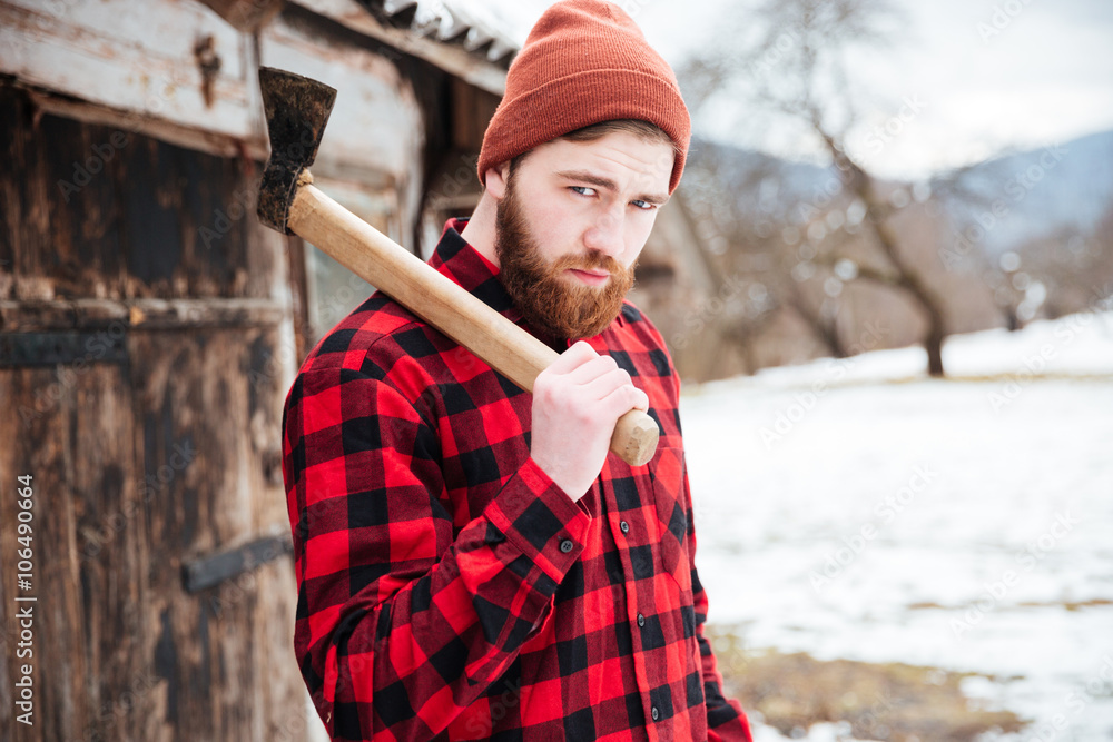 Wall mural handsome bearded man with axe in village