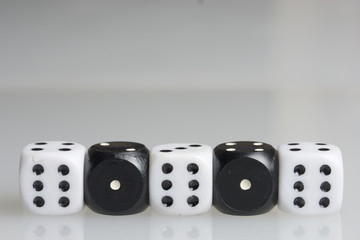 Dice. Playing cubes.  Cubes white with a value of six points arranged in a row. Alternating with cubes of black color with a value of one point. On a white background. There is room for text.
