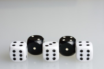 Dice. Playing cubes.  Cubes white with a value of six points arranged in a row. Alternating with cubes of black color with a value of one point. On a white background. There is room for text.