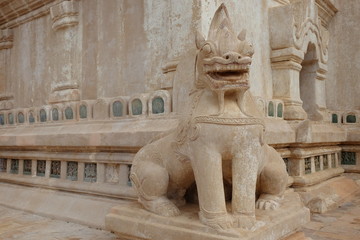 The stone statue of spiritual lion is standing in front of a temple in Bagan, Myanmar,