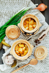 
National Russian , Ukrainian and Belarusian cuisine , baked potatoes with meat in the pot , onion , pepper, garlic , pickled cucumber and spices on a wooden background
