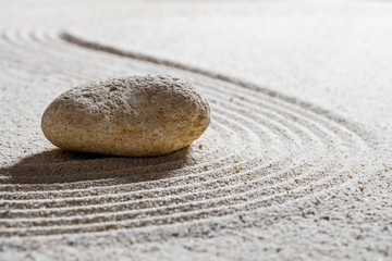 Fototapeta na wymiar zen sand still-life - textured stone on sinuous waves for concept of beauty spa or wellness with inner peace, closeup