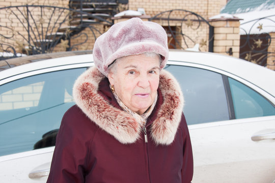 Cheerful elderly woman in winter near to the car