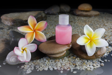 Obraz na płótnie Canvas shower gel liquid with flower frangipani on pebble rock and wate