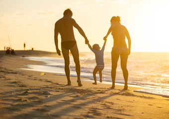 Happy family with little boy together at sunset