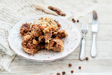 
Fried chicken liver with onions and spices on a wooden background