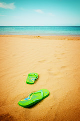 green sandals on sandy beach