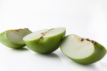 Sliced green apple half and two quarters on white background from side