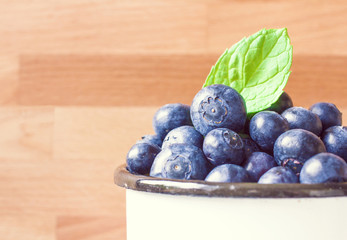 Fresh Blueberries with green mint leaf on wood