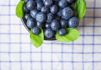 Fresh Blueberries with green mint leaves on white blue towel