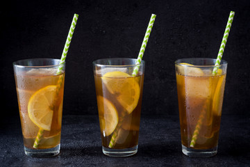 Ice tea with lemon. Black stone background
