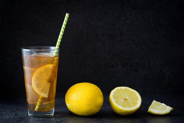 Ice tea with lemon. Black stone background
