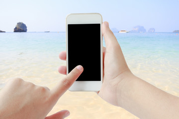 Female hands using cellphone on blurred beach background