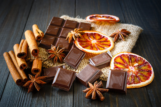 Dark chocolates with dry oranges, cinnamon and anise on burlap on rustic table