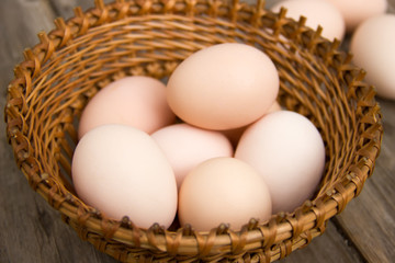Chicken eggs on a wooden table in a wicker basket close-up