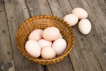 Chicken eggs on a wooden table in a wicker basket