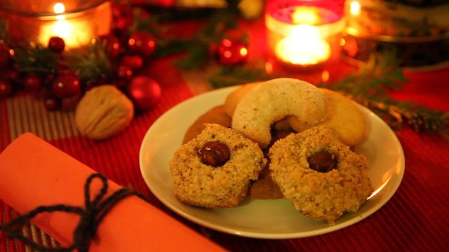 Weihnachts-Geb&auml;ck auf dem Weihnachtstisch mit festlichem Schmuck und Geschenk. Brennende Kerzen.
