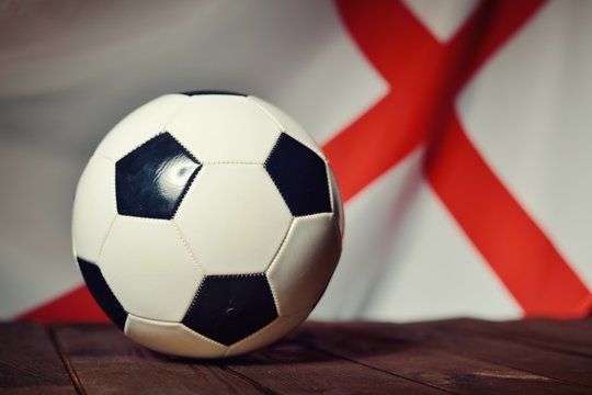 Flag of England with football on wooden boards as the background