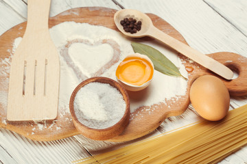 Pasta spaghetti with flour, egg on rustic wooden  background