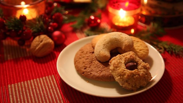 Weihnachts-Geb&auml;ck auf dem Weihnachtstisch mit festlichem Schmuck. Eine Hand nimmt die Pl&auml;tzchen weg, bis der Teller leer ist.