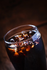Cola with crushed ice in a big sweaty glass, dark toned image, s