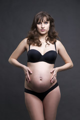 Obraz premium Young beauty and sexy caucasian pregnant woman in black lingerie on gray studio background