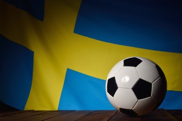 Fototapeta premium Flag of Sweden with football on wooden boards as the background.