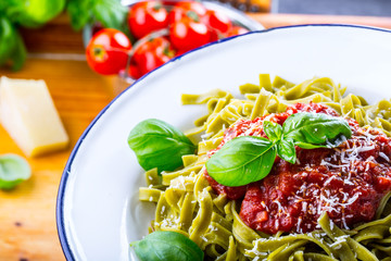 Pasta. Italian and Mediterranean cuisine. Pasta Fettuccine with tomato sauce basil leaves garlic and parmesan cheese. An old home kitchen with old kitchen utensils. Portion of on a fork