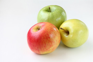 three apples on the table/red, yellow and green apples on the table