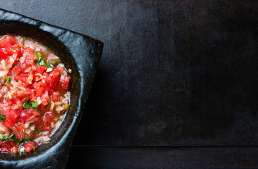 Mexican latin american tomato sauce salsa in stone mortar and sandwiches on black background
